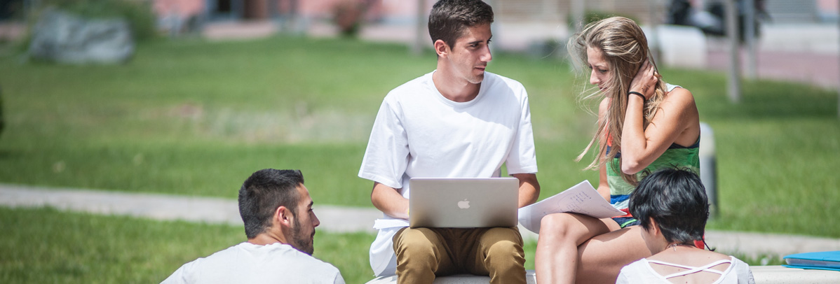estudiantes consultan un portátil en el campus